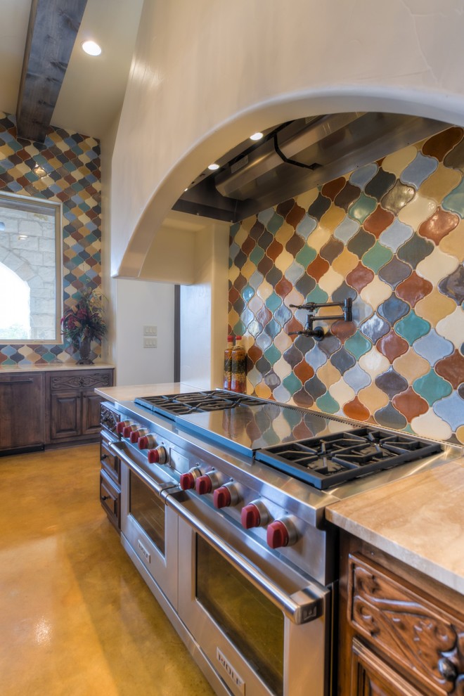 Design ideas for a large mediterranean l-shaped enclosed kitchen in Austin with a belfast sink, medium wood cabinets, multi-coloured splashback, stainless steel appliances and an island.