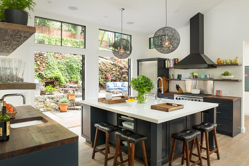 Contemporary kitchen in San Francisco with a submerged sink, shaker cabinets, wood worktops, metallic splashback, stainless steel appliances, medium hardwood flooring and an island.