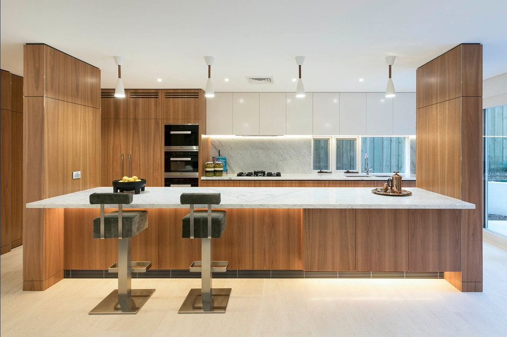 Cette image montre une cuisine américaine parallèle et encastrable design en bois brun avec un évier encastré, un placard à porte plane, une crédence blanche, fenêtre, îlot, un sol blanc et un plan de travail blanc.