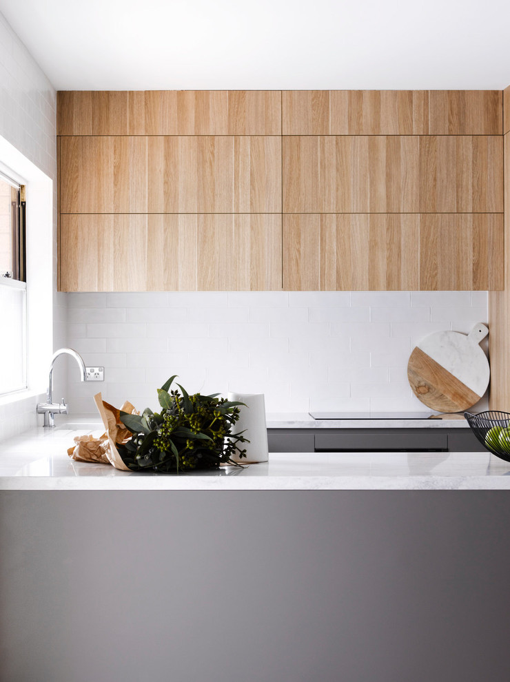 Photo of a small scandinavian u-shaped open plan kitchen in Sydney with recessed-panel cabinets, light wood cabinets, granite worktops, white splashback and an island.