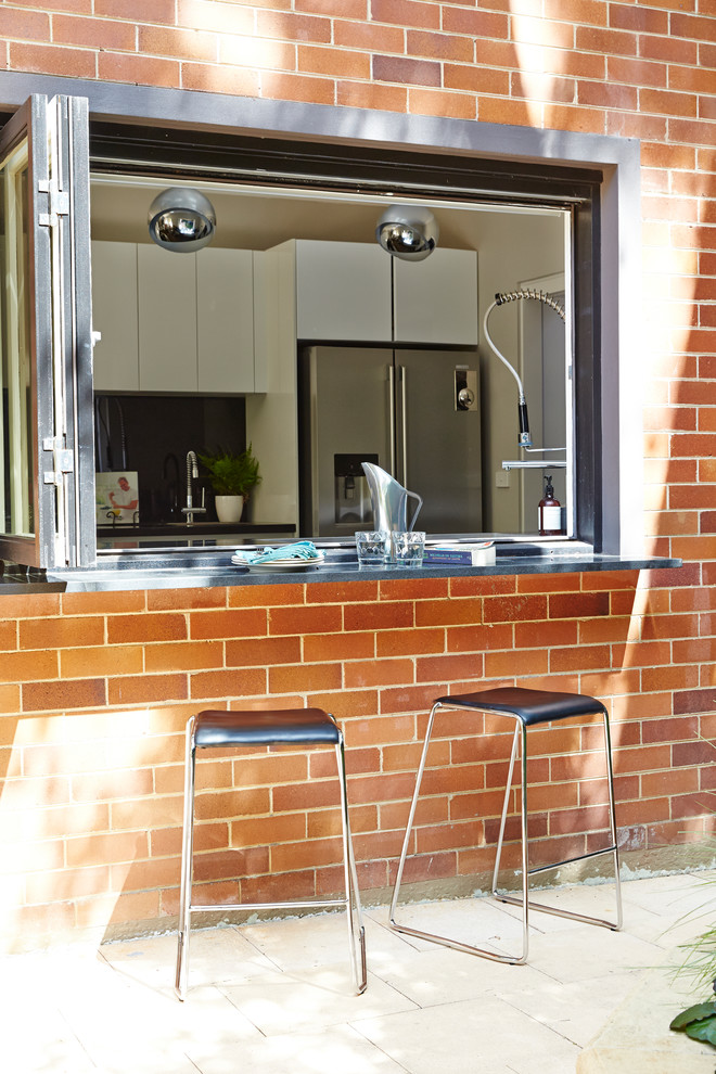 Modern inredning av ett mellanstort kök, med en dubbel diskho, bänkskiva i kvarts, svart stänkskydd, glaspanel som stänkskydd, rostfria vitvaror, mörkt trägolv, en köksö och brunt golv