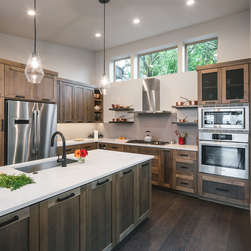 Inspiration for a mid-sized rustic l-shaped dark wood floor and brown floor kitchen remodel in Portland with shaker cabinets, quartz countertops, gray backsplash, ceramic backsplash, stainless steel appliances, an island, white countertops, an undermount sink and dark wood cabinets