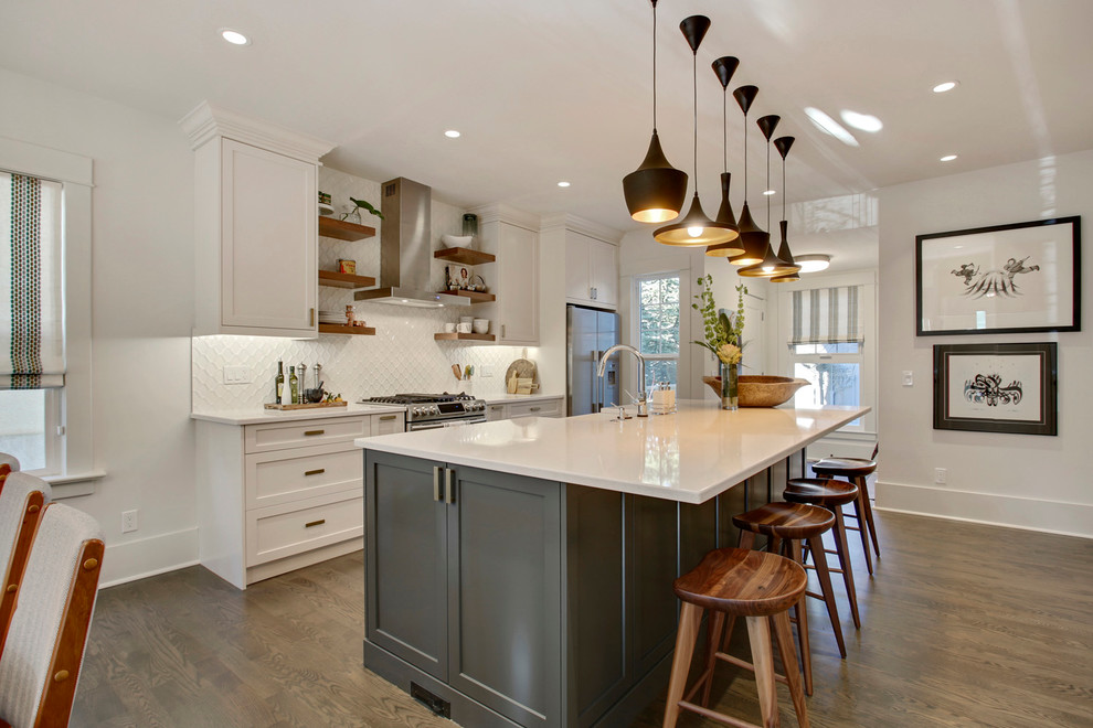 Example of a mid-sized transitional single-wall medium tone wood floor and brown floor eat-in kitchen design in Calgary with a farmhouse sink, shaker cabinets, white cabinets, white backsplash, stainless steel appliances and an island