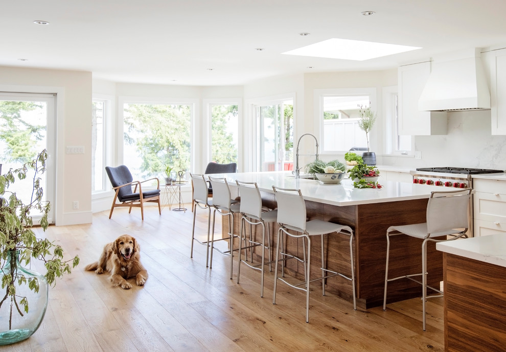 Example of a transitional light wood floor and brown floor kitchen design in Vancouver with an undermount sink, flat-panel cabinets, medium tone wood cabinets, quartz countertops, white backsplash, stone slab backsplash, stainless steel appliances and two islands