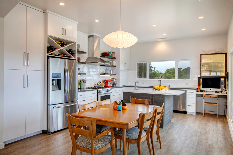 Open concept kitchen - large transitional l-shaped light wood floor open concept kitchen idea in San Diego with a single-bowl sink, flat-panel cabinets, white cabinets, quartz countertops, white backsplash, subway tile backsplash, stainless steel appliances and an island