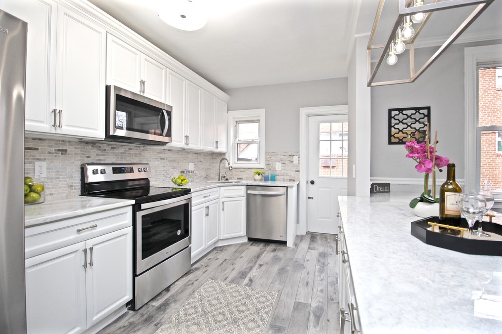 Idéer för små vitt kök, med en undermonterad diskho, luckor med upphöjd panel, vita skåp, granitbänkskiva, flerfärgad stänkskydd, stänkskydd i mosaik, rostfria vitvaror, laminatgolv, en köksö och grått golv