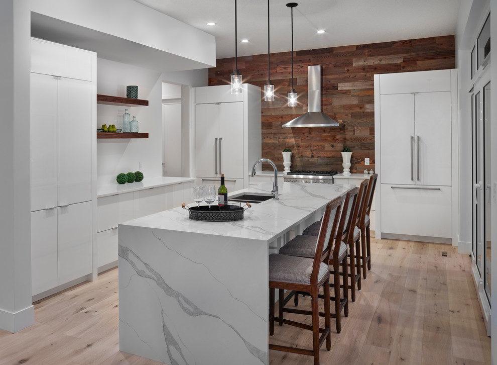 Inspiration for a mid-sized modern l-shaped light wood floor eat-in kitchen remodel in Edmonton with an undermount sink, flat-panel cabinets, white cabinets, marble countertops, white backsplash, stainless steel appliances and an island
