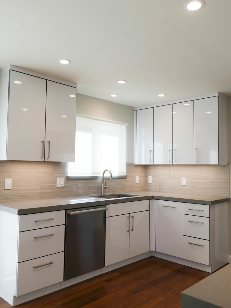 Idéer för att renovera ett mellanstort funkis grå grått kök, med en undermonterad diskho, släta luckor, vita skåp, bänkskiva i kvarts, grått stänkskydd, stänkskydd i porslinskakel, rostfria vitvaror, bambugolv och brunt golv