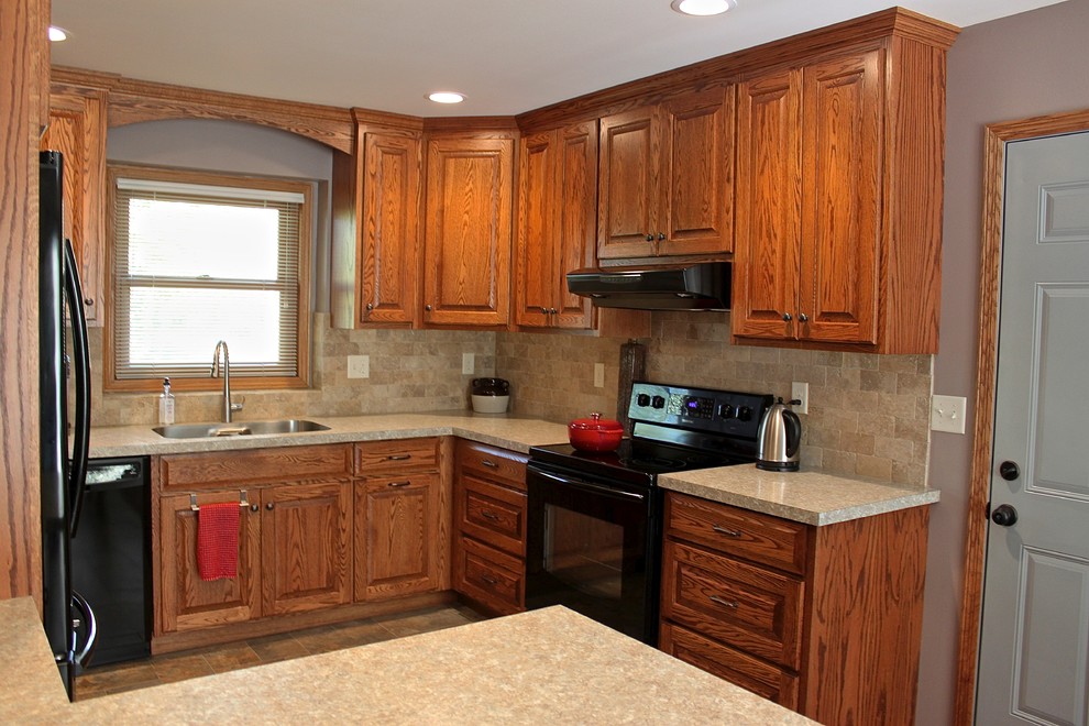 Photo of a medium sized traditional enclosed kitchen in Minneapolis with a double-bowl sink, raised-panel cabinets, medium wood cabinets, laminate countertops, beige splashback, stone tiled splashback, black appliances and no island.