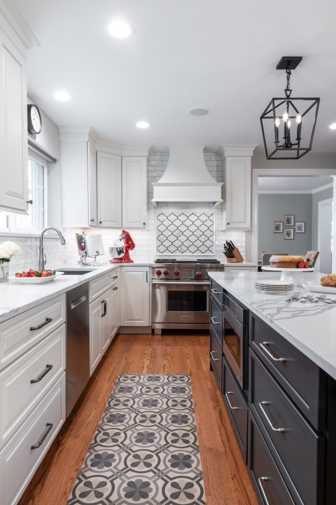 Large traditional kitchen in St Louis with a submerged sink, raised-panel cabinets, white cabinets, engineered stone countertops, white splashback, ceramic splashback, stainless steel appliances, medium hardwood flooring and white worktops.