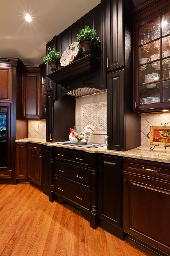Example of a large classic l-shaped medium tone wood floor and brown floor eat-in kitchen design in Atlanta with raised-panel cabinets, dark wood cabinets, granite countertops, beige backsplash, stone tile backsplash, colored appliances and beige countertops