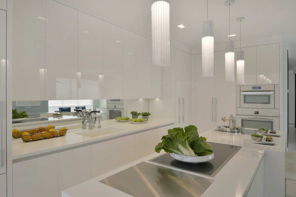 Small contemporary l-shaped enclosed kitchen in New York with an integrated sink, flat-panel cabinets, white cabinets, composite countertops, mirror splashback, white appliances, porcelain flooring, an island and beige floors.