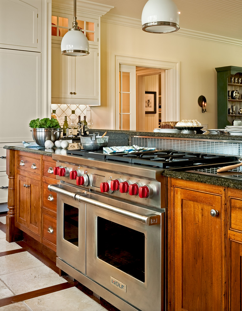 Elegant eat-in kitchen photo in New York with stainless steel appliances, recessed-panel cabinets, medium tone wood cabinets, a drop-in sink, granite countertops, multicolored backsplash and ceramic backsplash