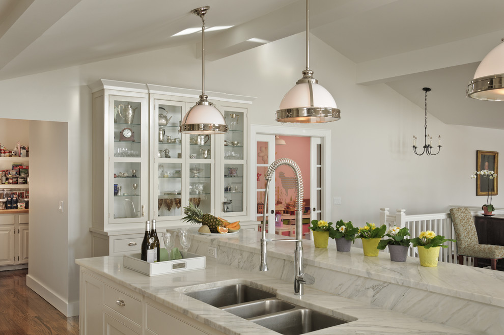 Cette image montre une cuisine américaine traditionnelle avec un évier 3 bacs, des portes de placard blanches, plan de travail en marbre, une crédence métallisée, une crédence en mosaïque et un électroménager en acier inoxydable.
