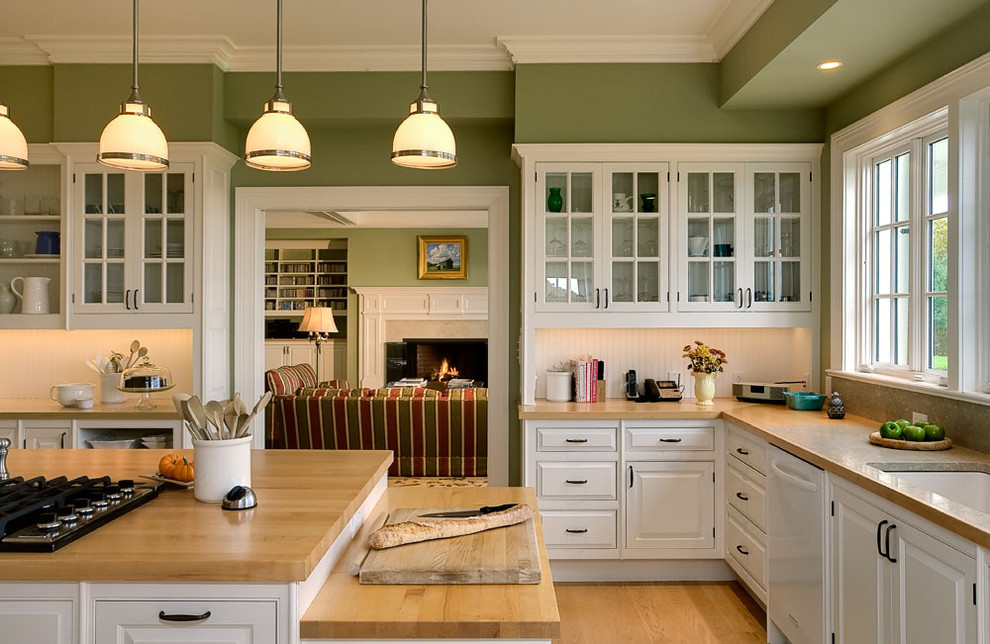 Inspiration for a timeless enclosed kitchen remodel in New York with glass-front cabinets, wood countertops, white cabinets, an undermount sink, white backsplash and white appliances