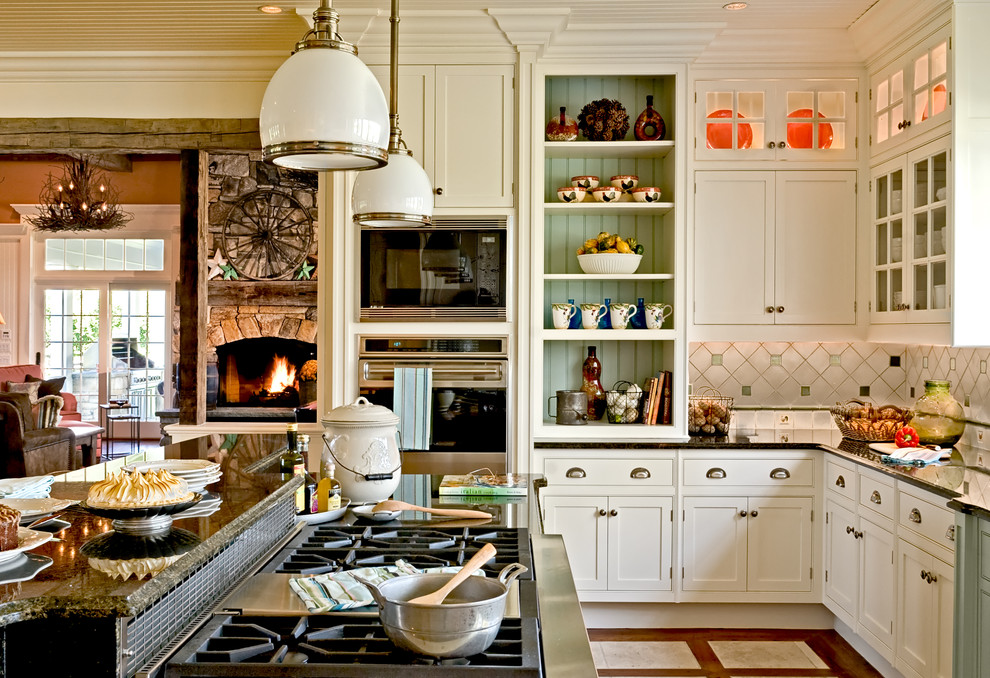 Example of a classic eat-in kitchen design in New York with recessed-panel cabinets, stainless steel appliances, white cabinets, granite countertops, multicolored backsplash, a farmhouse sink and ceramic backsplash