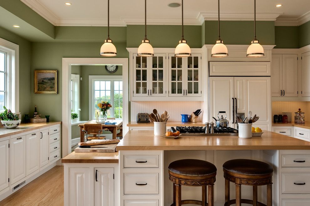 Elegant eat-in kitchen photo in New York with beaded inset cabinets, wood countertops, paneled appliances, white cabinets, an undermount sink and white backsplash