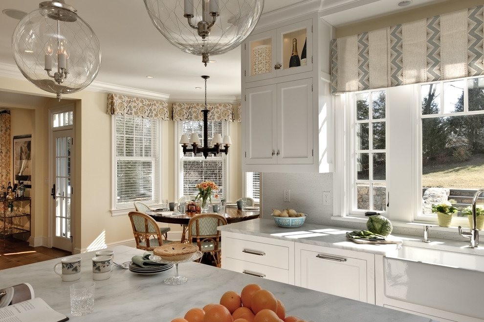 Eat-in kitchen - traditional eat-in kitchen idea in New York with a farmhouse sink, shaker cabinets, white cabinets, marble countertops and white backsplash