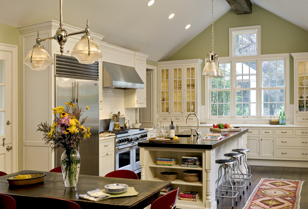 Example of a classic eat-in kitchen design in New York with beaded inset cabinets, white cabinets, stainless steel appliances, white backsplash, glass tile backsplash and marble countertops