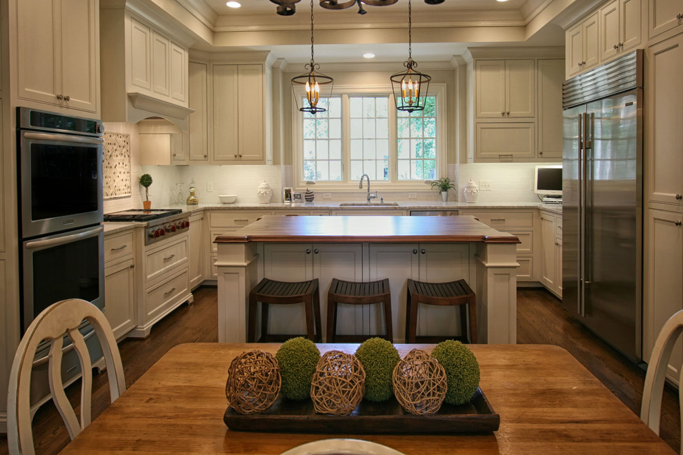 Example of a large transitional medium tone wood floor eat-in kitchen design in Charlotte with an undermount sink, flat-panel cabinets, white cabinets, white backsplash, subway tile backsplash, stainless steel appliances and an island