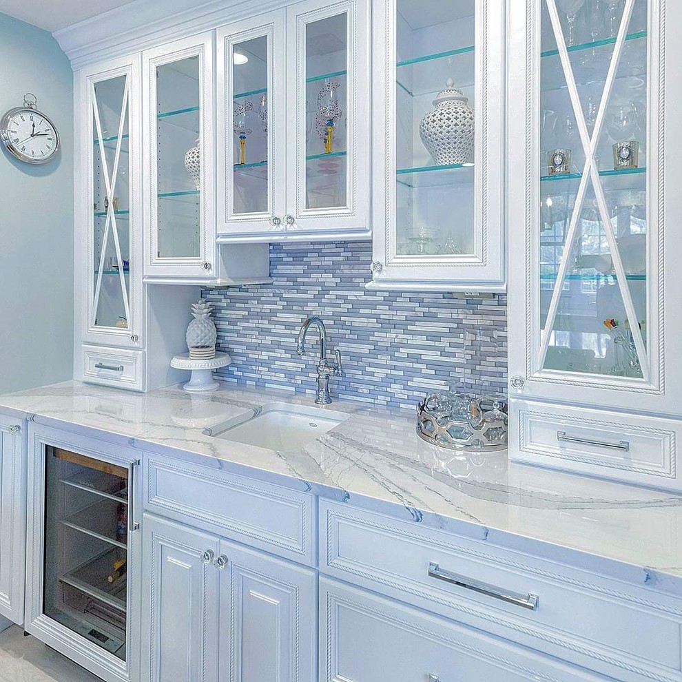 Eat-in kitchen - large traditional l-shaped porcelain tile and gray floor eat-in kitchen idea in New York with a single-bowl sink, raised-panel cabinets, white cabinets, quartz countertops, white backsplash, marble backsplash, stainless steel appliances, an island and white countertops
