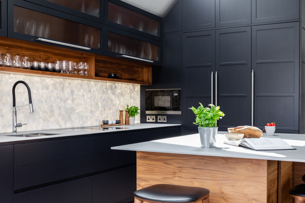 Photo of a small traditional open plan kitchen in London with raised-panel cabinets, composite countertops, white splashback, marble splashback, black appliances, light hardwood flooring, an island, beige floors and grey worktops.