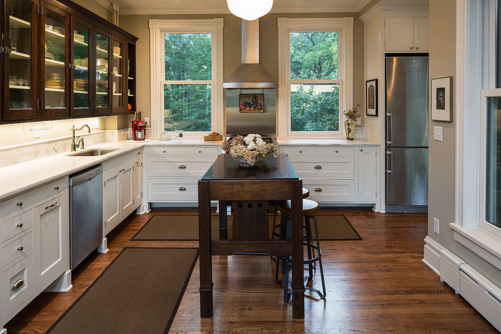 Esempio di una cucina american style con lavello sottopiano, ante di vetro, ante in legno bruno, top in marmo, paraspruzzi bianco, elettrodomestici in acciaio inossidabile e parquet scuro