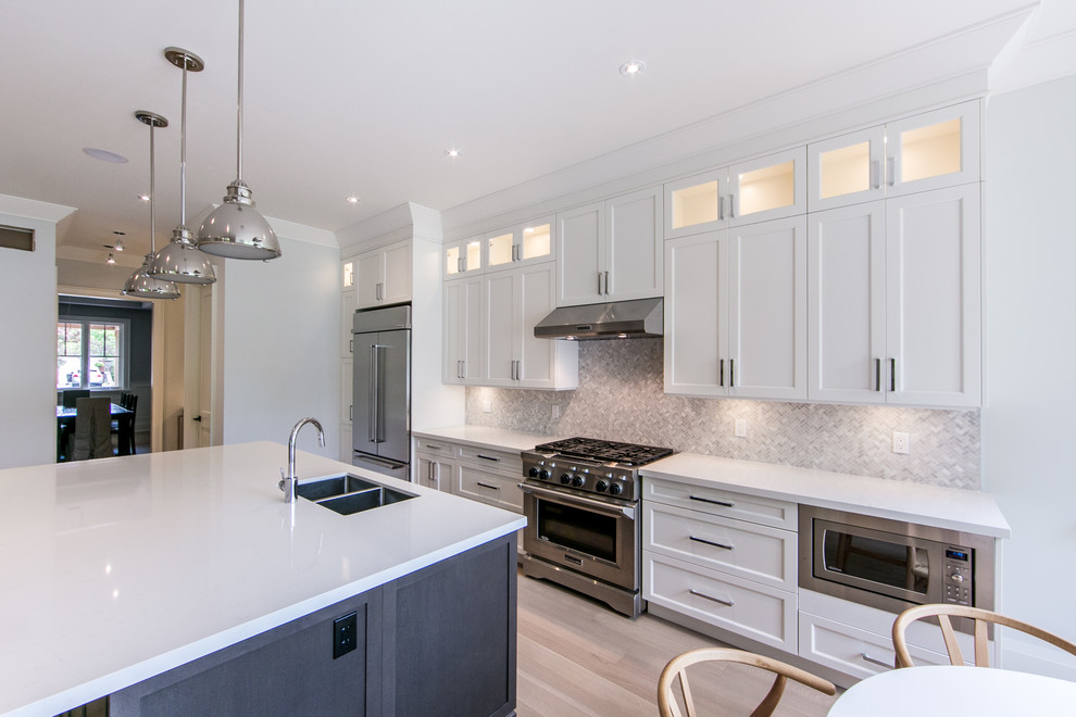 Inspiration for a large transitional single-wall light wood floor eat-in kitchen remodel in Toronto with shaker cabinets, white cabinets, quartzite countertops, gray backsplash, stainless steel appliances, an island, a double-bowl sink and mosaic tile backsplash