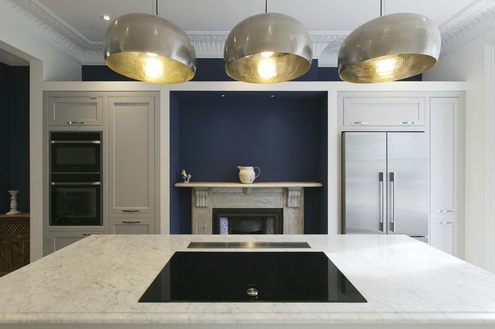 ロンドンにある高級な広いインダストリアルスタイルのおしゃれなキッチン (一体型シンク、シェーカースタイル扉のキャビネット、大理石カウンター、黒い調理設備、白いキッチンカウンター) の写真