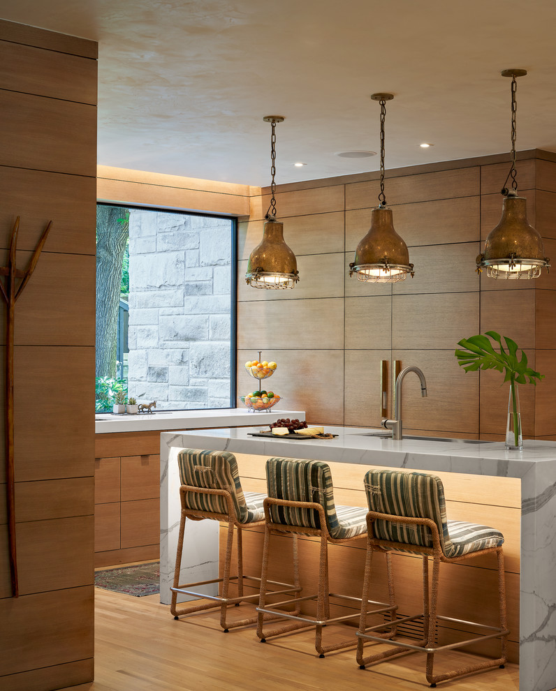 Moderne Küche in U-Form mit flächenbündigen Schrankfronten, hellbraunen Holzschränken, Rückwand-Fenster, braunem Holzboden, Kücheninsel, braunem Boden und weißer Arbeitsplatte in Austin