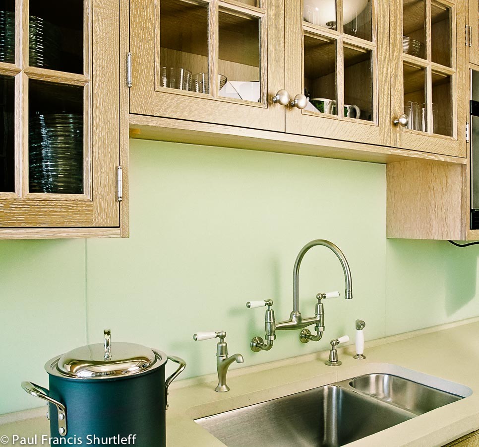 Inspiration for a small traditional galley kitchen pantry in New York with a submerged sink, beaded cabinets, distressed cabinets, concrete worktops, green splashback, glass sheet splashback, stainless steel appliances, dark hardwood flooring and no island.