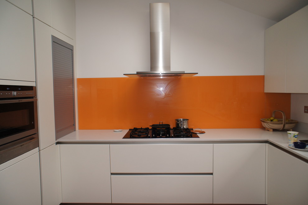 Bild på ett mellanstort funkis kök, med en enkel diskho, släta luckor, bänkskiva i koppar, orange stänkskydd, glaspanel som stänkskydd, rostfria vitvaror och vita skåp