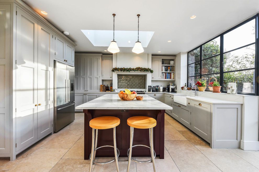 Inspiration for a transitional beige floor kitchen remodel in London with an island, a farmhouse sink, shaker cabinets, gray cabinets, gray backsplash, stainless steel appliances and white countertops