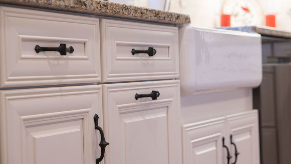 Bild på ett mellanstort funkis kök, med en rustik diskho, vita skåp, granitbänkskiva, vitt stänkskydd, stänkskydd i cementkakel, rostfria vitvaror, ljust trägolv, en köksö och brunt golv