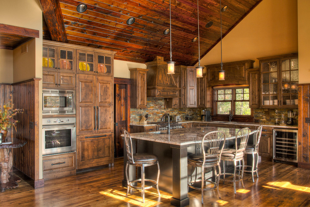 Foto di un cucina con isola centrale stile rurale con lavello sottopiano, ante con bugna sagomata, ante in legno bruno, paraspruzzi multicolore, elettrodomestici da incasso, parquet scuro e pavimento arancione