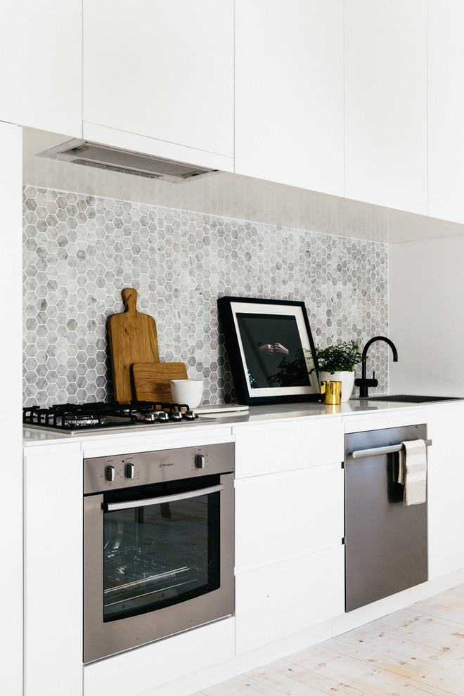 Diseño de cocina comedor lineal escandinava con salpicadero verde, salpicadero de azulejos de piedra y electrodomésticos de acero inoxidable