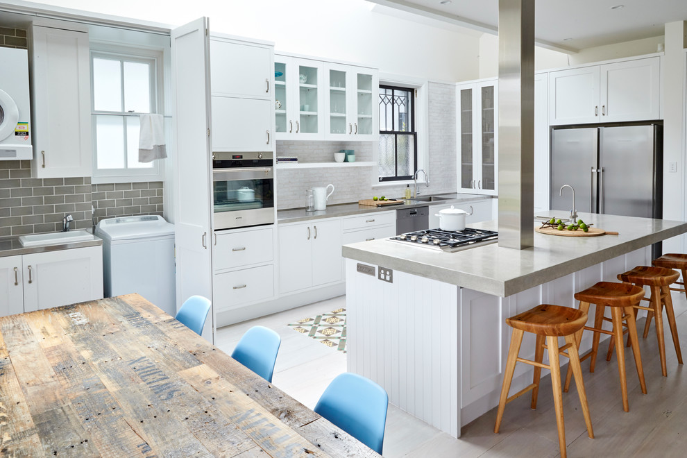 Große, Zweizeilige Moderne Wohnküche mit Schrankfronten im Shaker-Stil, weißen Schränken, Betonarbeitsplatte, Küchenrückwand in Weiß, Rückwand aus Porzellanfliesen, Küchengeräten aus Edelstahl, hellem Holzboden und Kücheninsel in Sydney