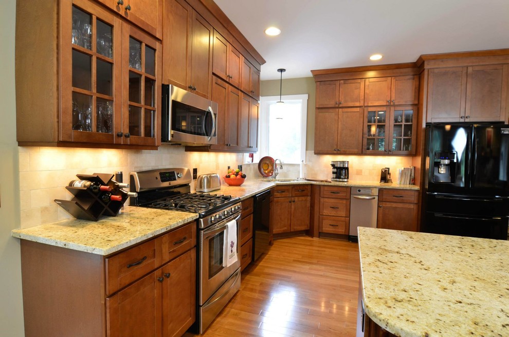 Bild på ett mellanstort amerikanskt kök, med en undermonterad diskho, skåp i shakerstil, skåp i mörkt trä, granitbänkskiva, beige stänkskydd, stänkskydd i keramik, rostfria vitvaror, mellanmörkt trägolv och en köksö