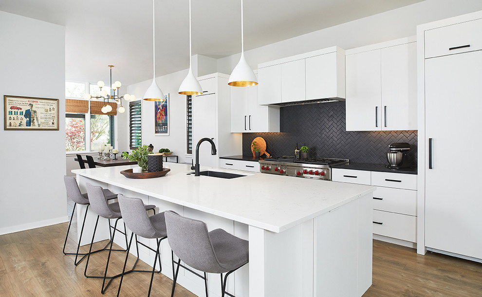 Inspiration for a large contemporary galley medium tone wood floor and brown floor eat-in kitchen remodel in Grand Rapids with an undermount sink, flat-panel cabinets, white cabinets, quartz countertops, black backsplash, ceramic backsplash, an island, white countertops and paneled appliances