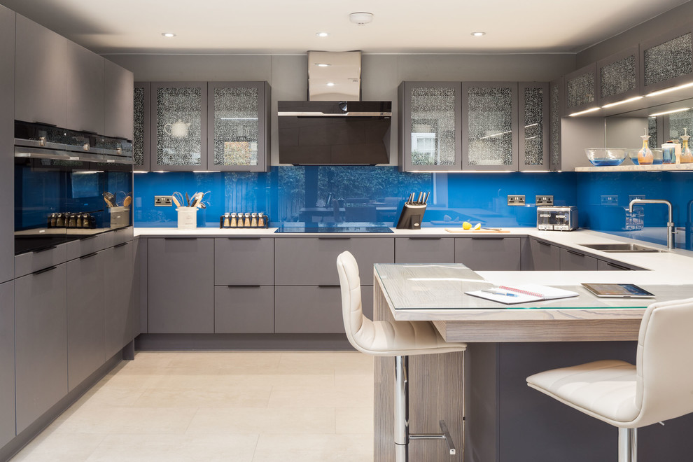 Inspiration for a medium sized contemporary u-shaped kitchen in Other with grey cabinets, wood worktops, blue splashback, glass sheet splashback, black appliances, limestone flooring, a breakfast bar, yellow floors, white worktops, a double-bowl sink and glass-front cabinets.