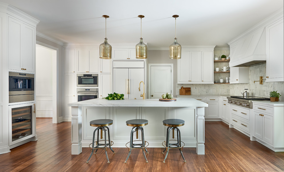 Example of a transitional l-shaped medium tone wood floor enclosed kitchen design in Charlotte with shaker cabinets, white cabinets, white backsplash, paneled appliances, an island and white countertops