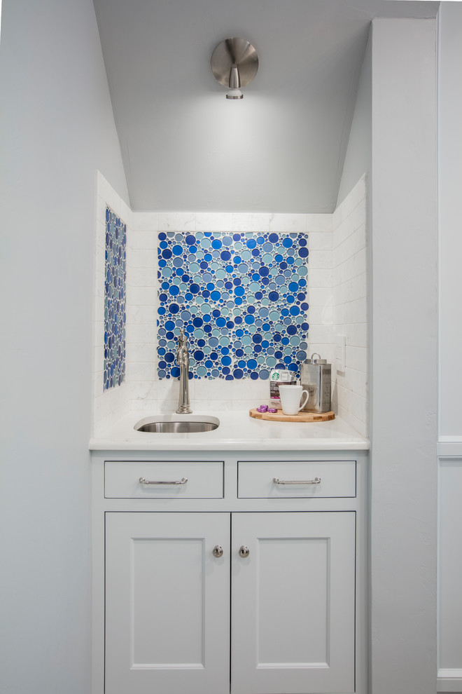 Inredning av ett klassiskt mellanstort vit vitt kök, med en undermonterad diskho, luckor med infälld panel, grå skåp, bänkskiva i kvarts, blått stänkskydd, stänkskydd i glaskakel, rostfria vitvaror, marmorgolv, en köksö och flerfärgat golv