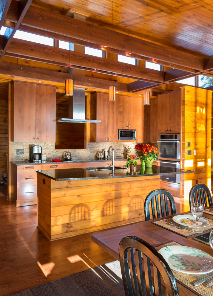 This is an example of a large rustic u-shaped open plan kitchen in Minneapolis with a submerged sink, flat-panel cabinets, medium wood cabinets, engineered stone countertops, multi-coloured splashback, stone tiled splashback, stainless steel appliances, medium hardwood flooring and an island.