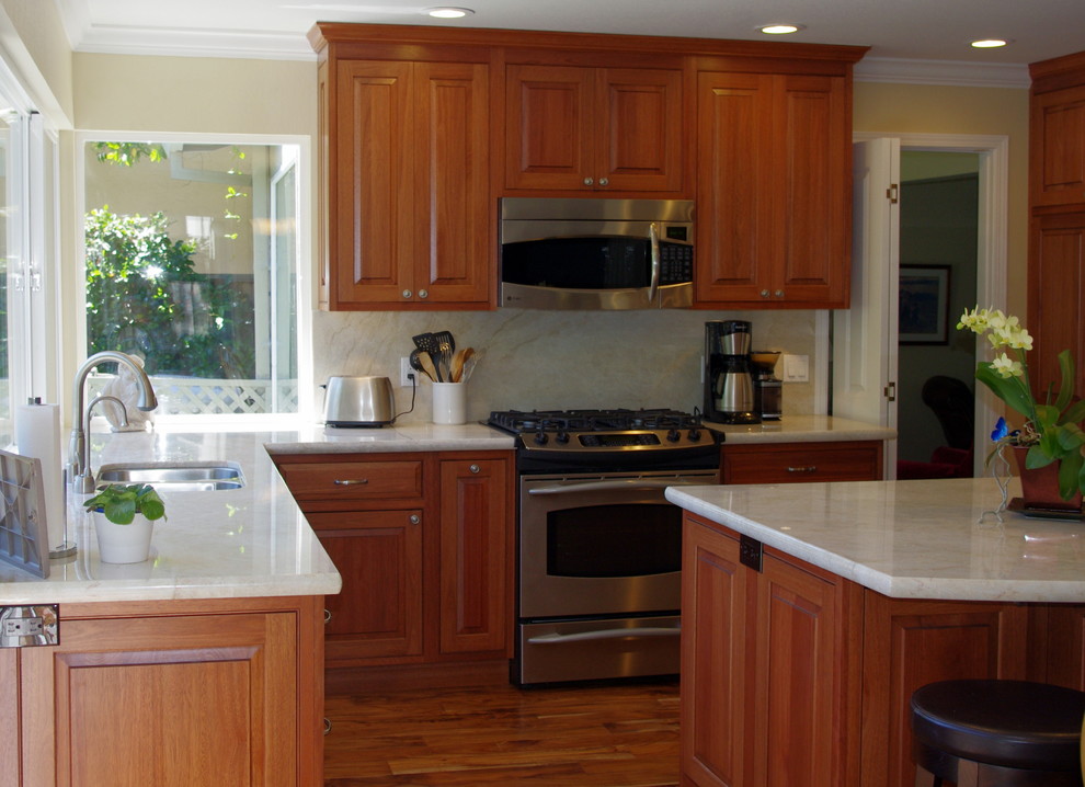 Exempel på ett mellanstort klassiskt kök, med luckor med upphöjd panel, skåp i mellenmörkt trä, granitbänkskiva, beige stänkskydd, stänkskydd i keramik, rostfria vitvaror och en köksö