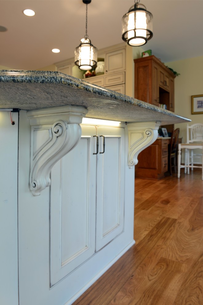 Ejemplo de cocina comedor tradicional con puertas de armario blancas, encimera de granito, electrodomésticos blancos y una isla