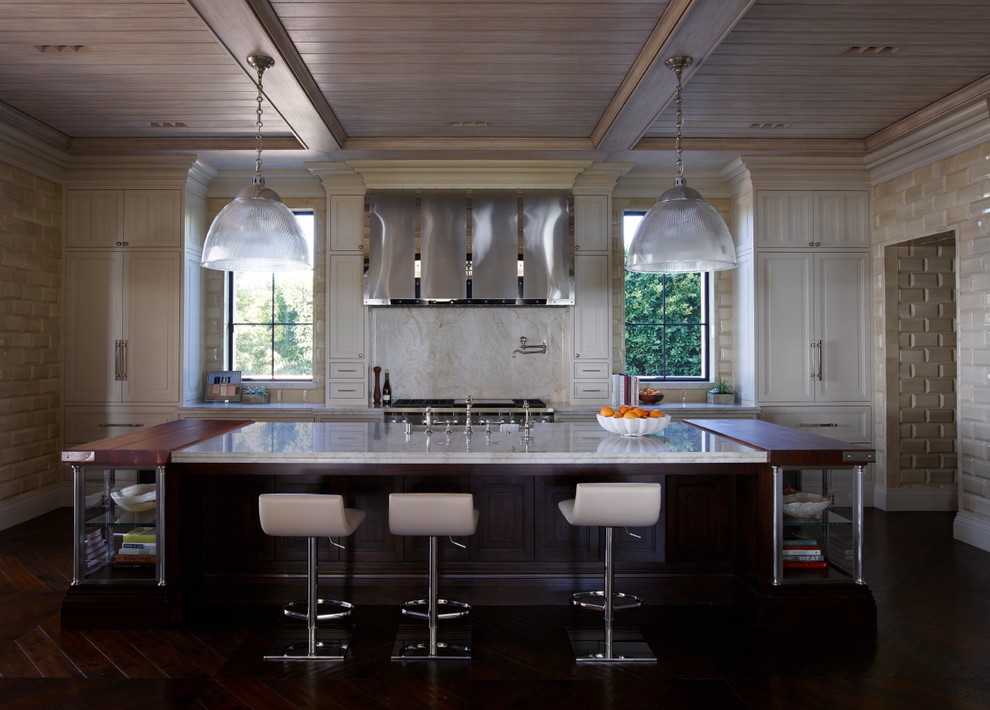 Bild på ett medelhavsstil kök, med en undermonterad diskho, luckor med infälld panel, vita skåp, marmorbänkskiva, rostfria vitvaror, mörkt trägolv och en köksö