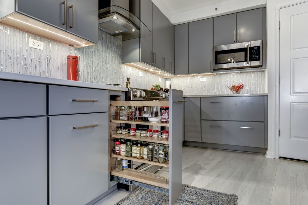 ワシントンD.C.にある高級な中くらいなコンテンポラリースタイルのおしゃれなキッチン (シングルシンク、フラットパネル扉のキャビネット、グレーのキャビネット、クオーツストーンカウンター、黄色いキッチンパネル、ガラスタイルのキッチンパネル、シルバーの調理設備、ラミネートの床、白い床) の写真