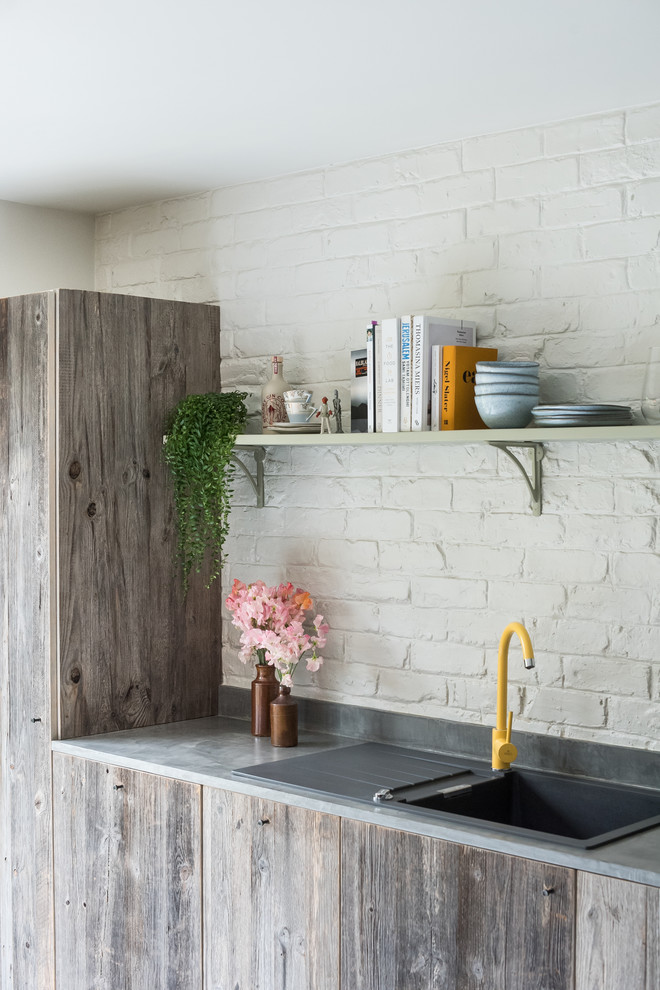 Idéer för ett mellanstort eklektiskt grå linjärt kök med öppen planlösning, med en enkel diskho, släta luckor, skåp i mellenmörkt trä, bänkskiva i betong, vitt stänkskydd, stänkskydd i tegel, rostfria vitvaror, en köksö och vitt golv