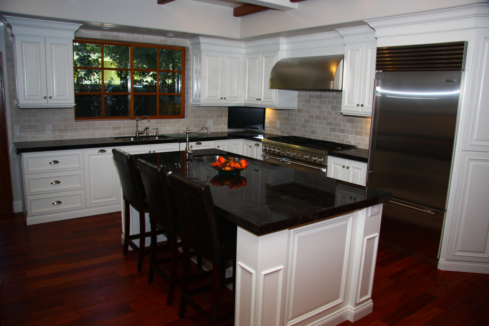 Idéer för att renovera ett stort vintage svart svart kök, med en undermonterad diskho, luckor med upphöjd panel, vita skåp, granitbänkskiva, beige stänkskydd, stänkskydd i travertin, rostfria vitvaror, mellanmörkt trägolv, en köksö och rött golv