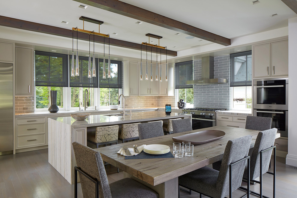 Transitional l-shaped brown floor eat-in kitchen photo in New York with an undermount sink, recessed-panel cabinets, beige cabinets, gray backsplash, subway tile backsplash, stainless steel appliances, an island and multicolored countertops